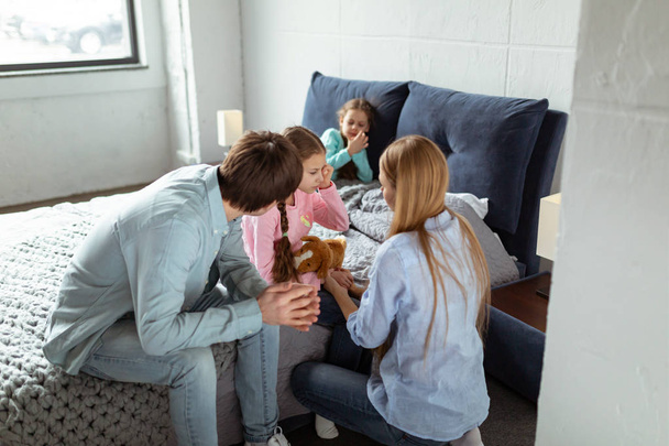 Giovani genitori seduti in camera da letto e rassicurare il loro pianto dauther
 - Foto, immagini