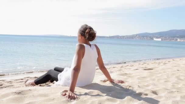 Vue arrière d'une adolescente allongée sur une plage de sable blanc
 - Séquence, vidéo