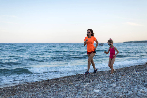 Active lifestyle: morning jogging along the beach. Mom and daugh - Foto, Imagen