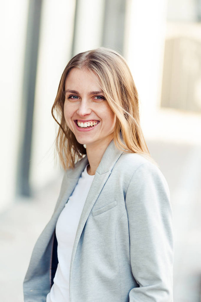 Portrait of beautiful smiling blonde young woman near office company - Zdjęcie, obraz