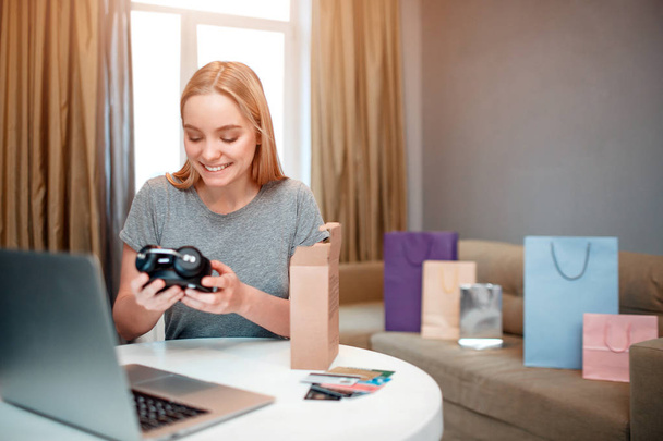 Online shopping at home. Young blonde shopper is happy about fashion purchase, ordered and delivered by internet - Fotoğraf, Görsel