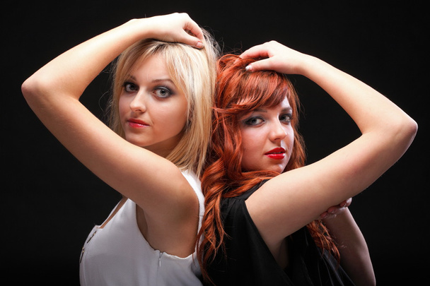 two happy young girlfriends black background - 写真・画像