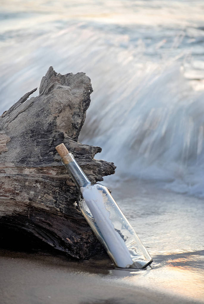 mensagem em uma garrafa que inclina-se na madeira à deriva na praia com onda
 - Foto, Imagem