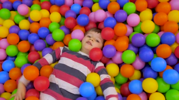 A kisfiú játszik a készletben Műanyag golyók a gyerekszobában. A gyerek az úszás. Közeli, valós időben, mesterséges fény, zárt térben. Mentális egészség fogalmát. Montessori koncepció. - Felvétel, videó