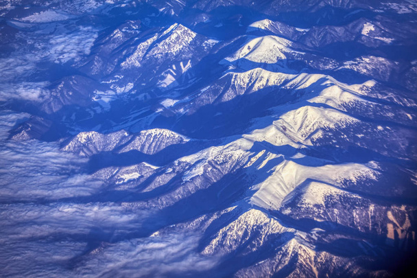 Luchtfoto van hoge bergen vallende sneeuw - Foto, afbeelding