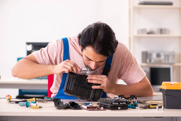 Genç bir erkek müteahhit bilgisayar tamir ediyor.   - Fotoğraf, Görsel