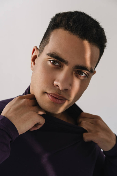 Mixed race fashion model posing for pictures in studio isolated on white background. Close up portrait of attractive African American man with emotional face in stylish purple turtleneck - Фото, изображение