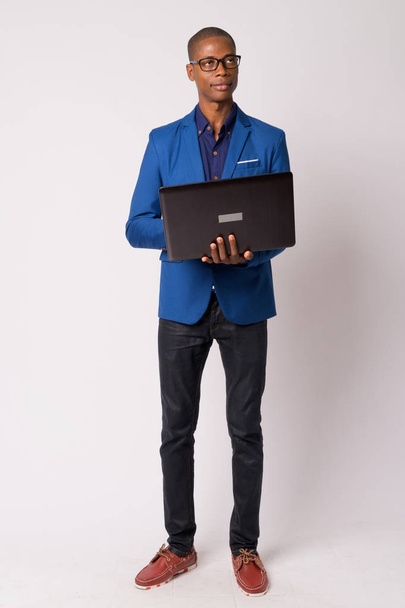 Całego ciała strzał młody łysy biznesmen Afryki myślenia podczas korzystania z laptopa - Zdjęcie, obraz