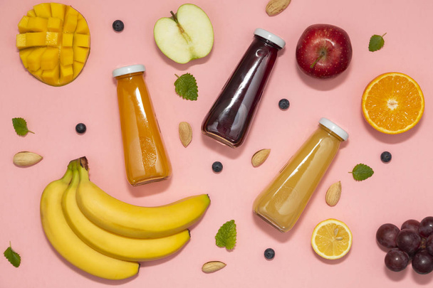 Colorful smoothies in bottles with fresh fruits on pink background. Flat lay. top view. Natural Organic Food Style.  - Fotó, kép