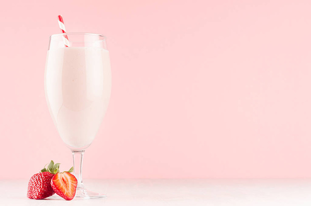 Fresh strawberry milkshake with straw and slice juicy berry in gentle graceful soft pink interior, copy space. - Foto, afbeelding