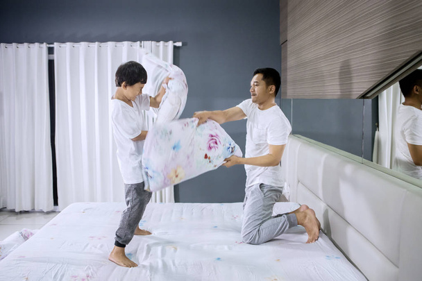 Boy making pillow fight with his father - Foto, afbeelding