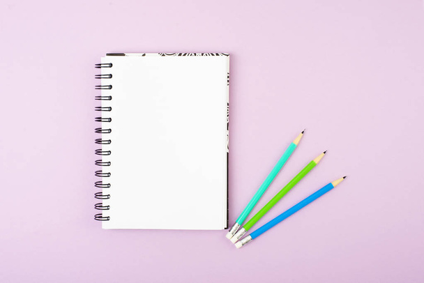 Blank notebook and color pencils on pink background - Фото, изображение