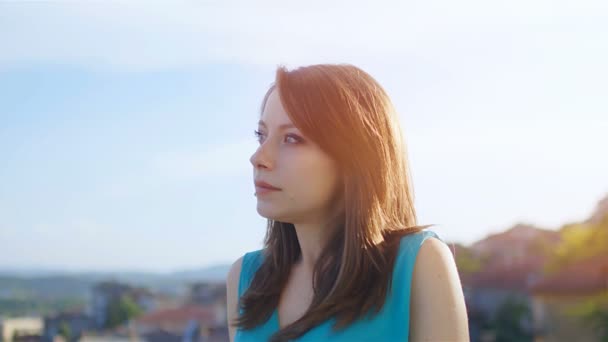 Portret van een mooie blanke jonge vrouw kijkend naar de camera bij zonsondergang, 4k - Video