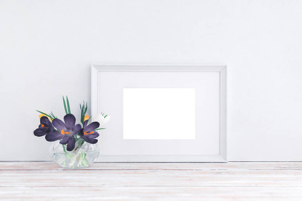 Empty white wooden frame and flowers in vase on white background with copy space. Mockup. - Photo, Image