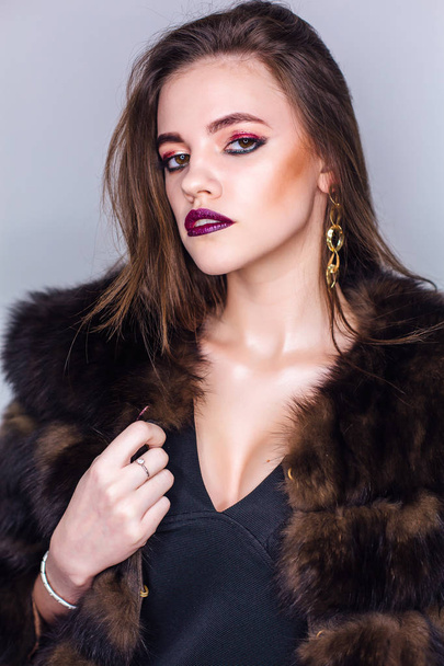 Beauty portrait of a woman with bright colorful make-up dressed in a fur coat - Фото, зображення