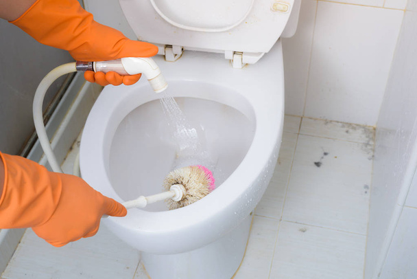 Hands in Orange gloves cleaning WC, Toilet, lavatory using brush - Fotoğraf, Görsel