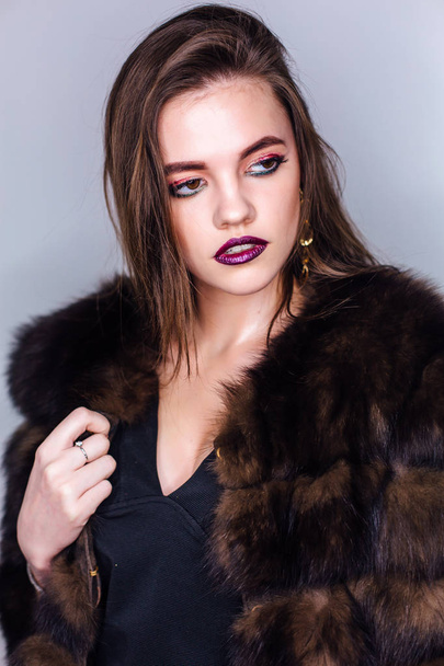 Beauty portrait of a woman with bright colorful make-up dressed in a fur coat - Foto, afbeelding