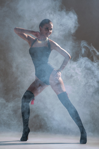 Modern style dancer posing on a studio grey background in fog - Фото, зображення