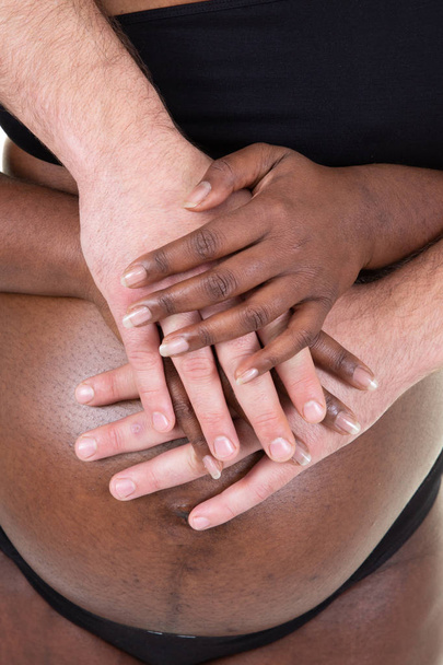 mestiza manos tocando madre africana americana vientre con caucásico padre
 - Foto, imagen
