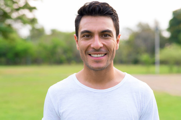 公園で笑っている幸せな若いハンサムなヒスパニック系男の顔 - 写真・画像