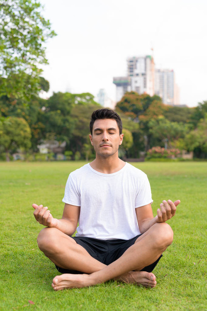 Młody przystojny mężczyzna Hiszpanie medytacji w parku na zewnątrz - Zdjęcie, obraz
