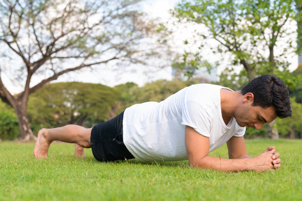 Profilbild eines jungen hübschen hispanischen Mannes beim Planken im Park - Foto, Bild