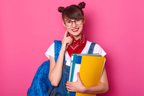 Dark haired student with blue bag, holds colourful paper folder, - Фото, зображення