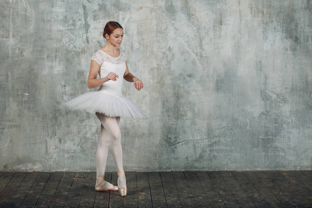 Bailarina femenina. Joven hermosa bailarina de ballet, vestida con traje profesional, zapatos puntiagudos y tutú blanco
. - Foto, imagen