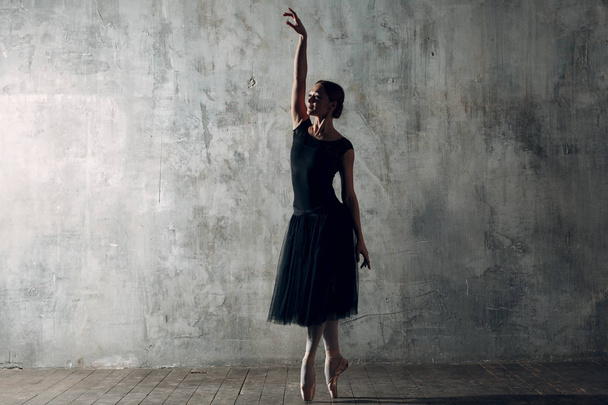 Mulher bailarina. Jovem mulher bonita bailarina de balé, vestida com roupa profissional, sapatos pontiagudos e tutu preto
. - Foto, Imagem