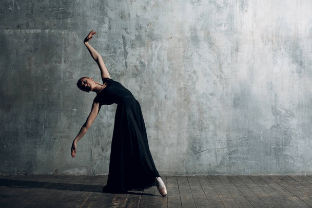 Ballerina female. Young beautiful woman ballet dancer, dressed in professional outfit, pointe shoes and black dress. - Fotoğraf, Görsel