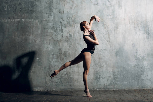 Балерина женщина. Молодая красивая балетная танцовщица, одетая в профессиональный костюм, пуанты и черное тело
. - Фото, изображение