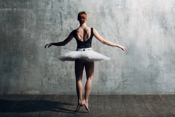 Γυναικεία μπαλαρίνα. Χορευτής μπαλέτου νεαρή όμορφη γυναίκα, ντυμένη με επαγγελματική στολή, παπούτσια pointe, Τουτού μαύρη κορυφή και λευκό. - Φωτογραφία, εικόνα
