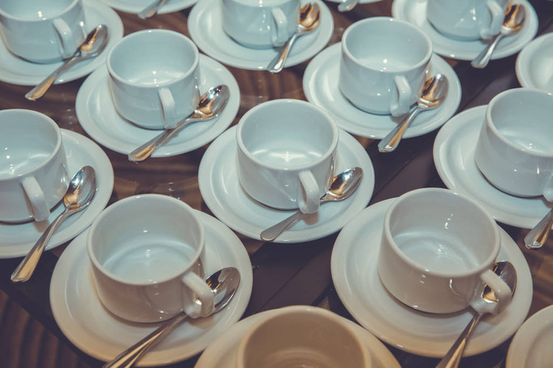 Κοντινό πλάνο βρώμικο καφέ Κύπελλο και κουτάλι ρύθμιση σε άσπρο πιατάκι και το ξύλινο τραπέζι μετά από να πιει το πρωί σε στυλ vintage. Κύπελλο - Φωτογραφία, εικόνα