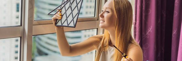 Молодая женщина делает макияж сидя у окна с панорамным видом на небоскребы и большой город Баннер, длинный Формат
 - Фото, изображение