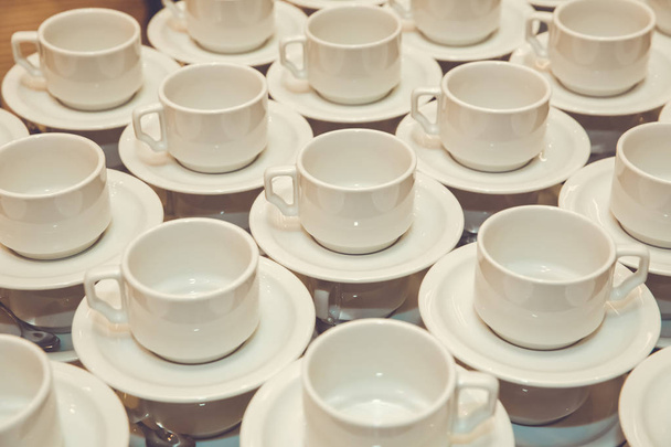 Закройте чашку грязного кофе и ложку посадки на белое блюдце и деревянный стол после питья утром в винтажном стиле
. - Фото, изображение