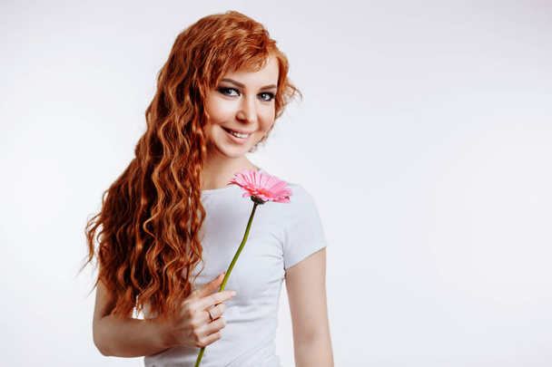 Attractive young woman holding a flower in her hands - Foto, Imagen