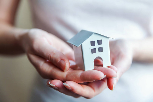 Vrouwelijke vrouw handen houden miniatuur wit speelgoed huis - Foto, afbeelding