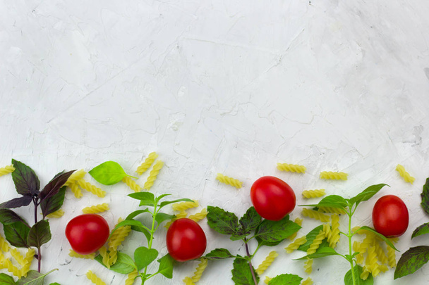 small ripe tomatoes, fresh basil ,pasta  top view flat lay frame white concrete background with empty space  for cooking recepies or product placement - 写真・画像