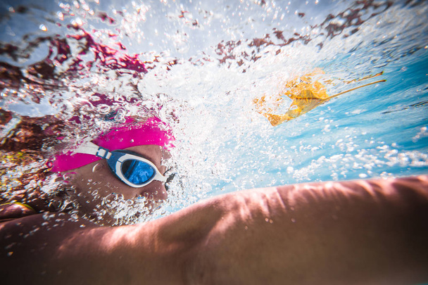 Close up wide angle photo of a female swimmer underwater in a swimming pool - Foto, Imagen