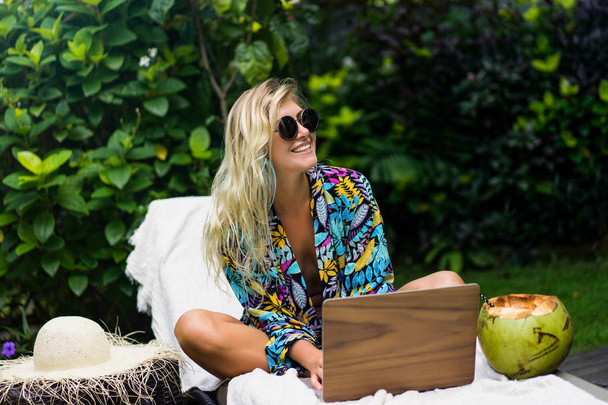 Woman freelancer, travel blogger works on a laptop. sitting on a - Foto, Imagen
