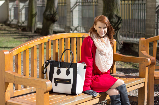 redhaired woman crossing sitting on the bench in park - Photo, Image
