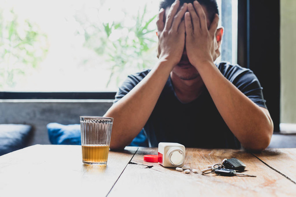 Depresión hombre mano en su cara con un vaso de alcohol y pastillas
  - Foto, imagen