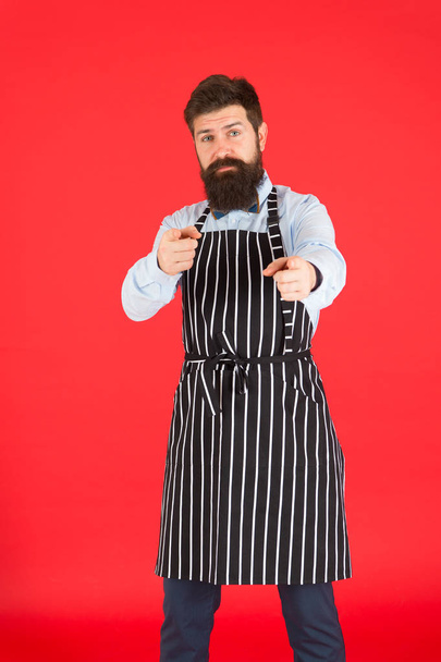 Happy to cook for you. Modern cafe concept. Cooking modern meals. Man with beard cook hipster apron. Hipster chef cook red background. Bearded man chef cooking. Hipster cooking home or restaurant - Foto, afbeelding