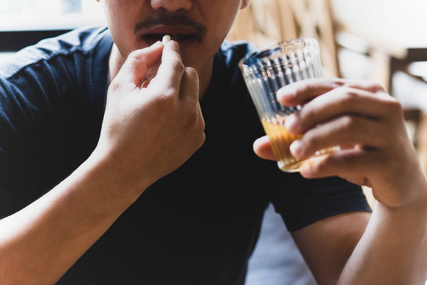 Depression man taking pills with glass of alcohol. - Photo, Image