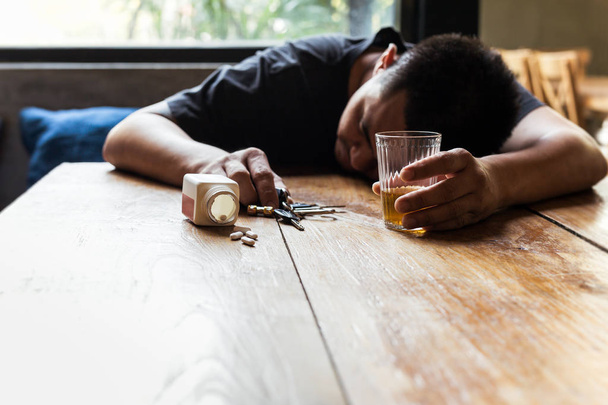 Drunk man hand holding glass of whiskey and car key sleeping on  - Photo, Image