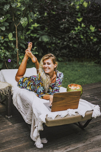 Woman freelancer, travel blogger works on a laptop. sitting on a - Fotoğraf, Görsel