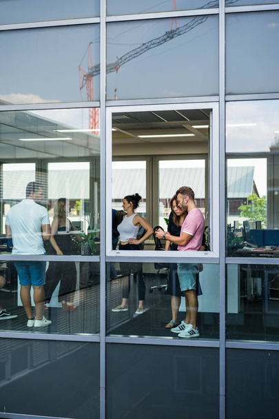 group of young people standing in an office with a large window - Фото, изображение