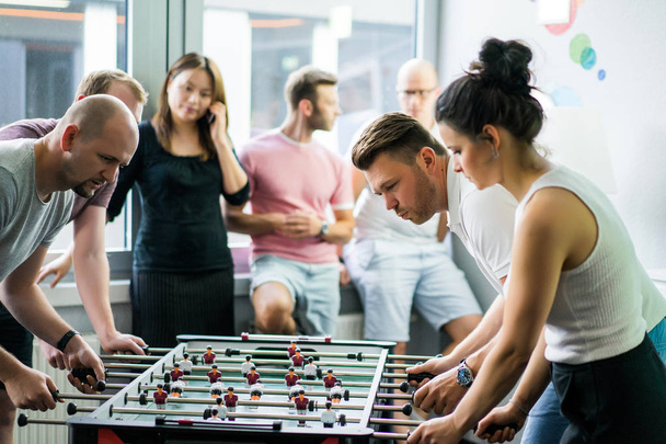 happy managers playing table football at office and having fun together - Fotoğraf, Görsel