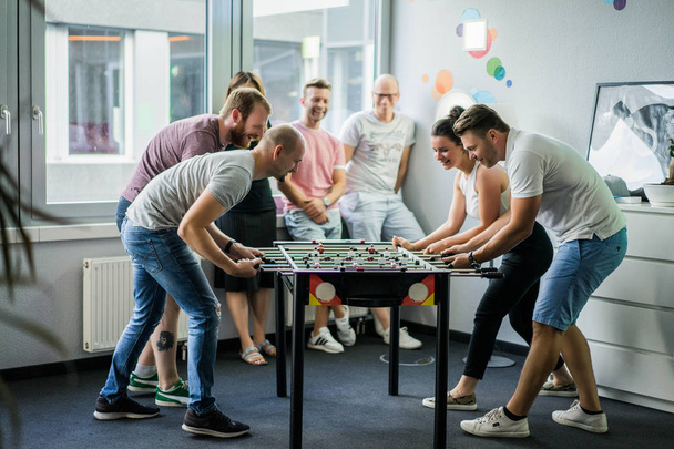 happy managers playing table football at office and having fun together - Фото, изображение