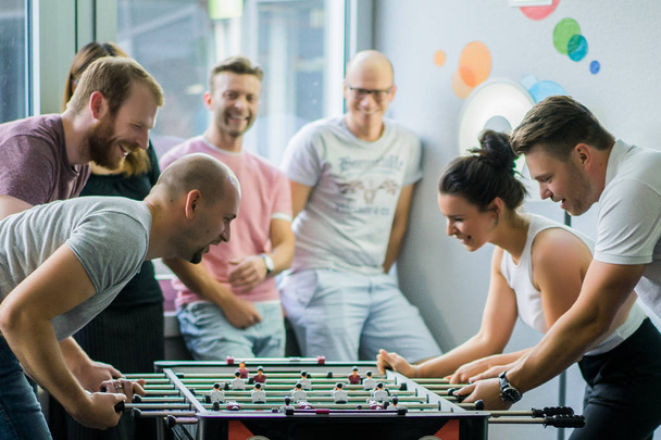 happy managers playing table football at office and having fun together - Fotó, kép